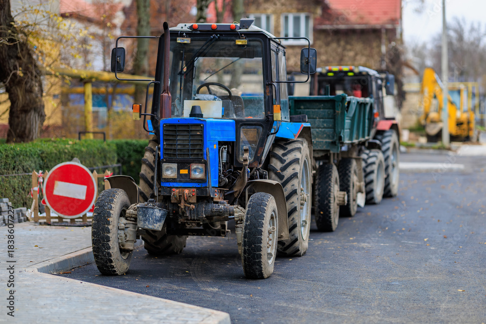 Obraz premium Blue tractor on urban street with trailers during road construction