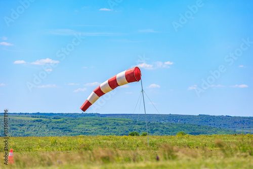 Red and white windsock on airfield amid clear blue sky and lush greenery. May 31, 2025 Vadul lui Voda Moldova