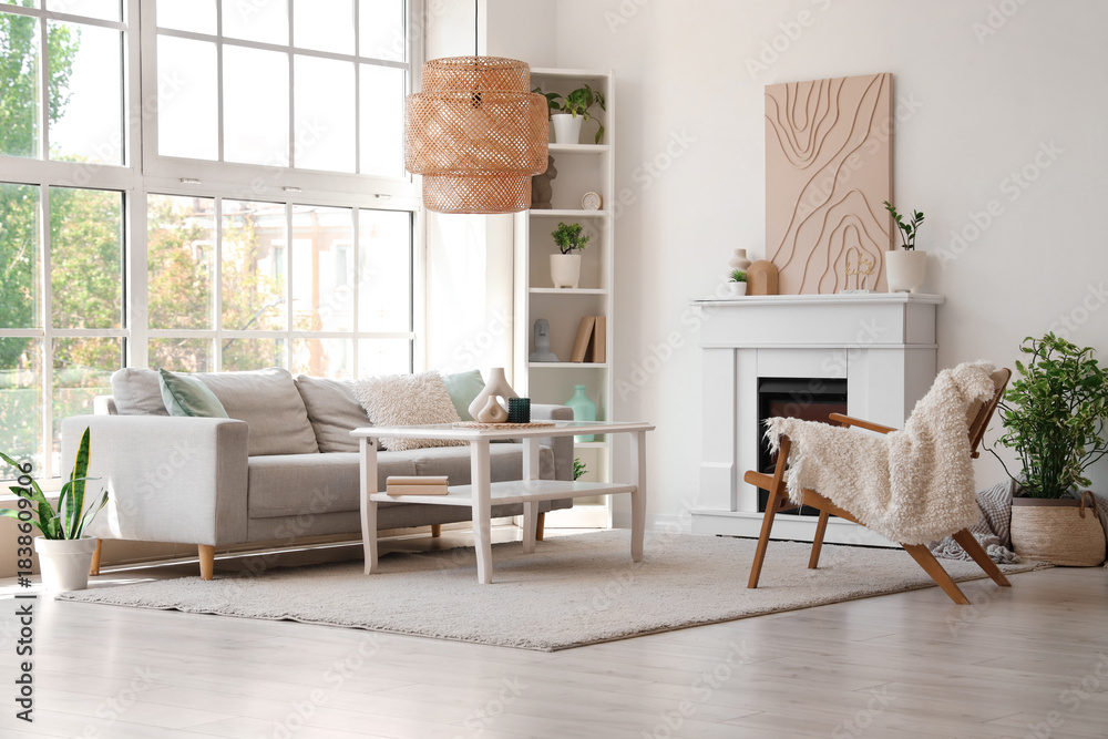 Fototapeta premium Fireplace, table sofa and armchair in interior of light living room
