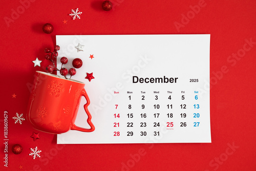 A vibrant December 2025 calendar with a red background, Christmas decorations, and a red mug creates a festive mood.