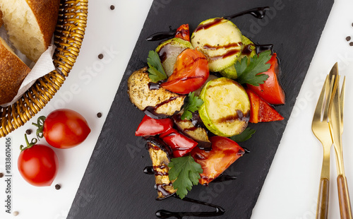 Vegetarian grilled vegetable salad with tomatoes. Serving a delicious eggplant, courgette, sweet pepper and tomato salad.