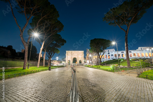 Arch of Constantine at night in Rome. Text translation "Senate dedicated this Arch to Constantine"