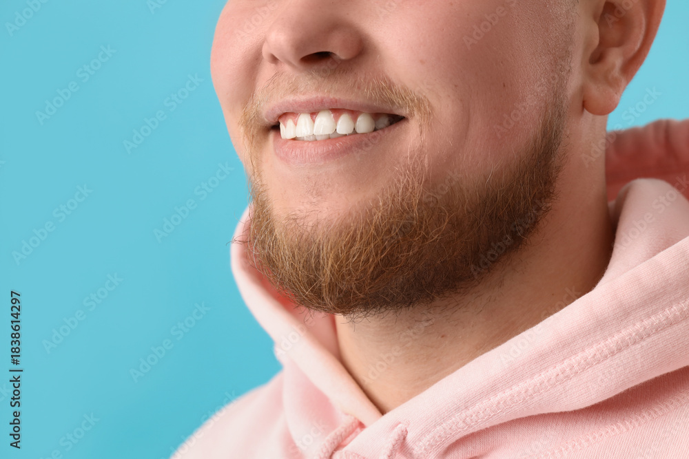 Obraz premium Smiling young bearded man on blue background, closeup
