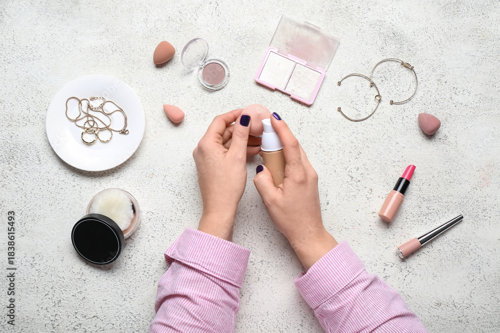 Fototapeta premium Female hands with different decorative cosmetics, accessories and makeup sponges on white background