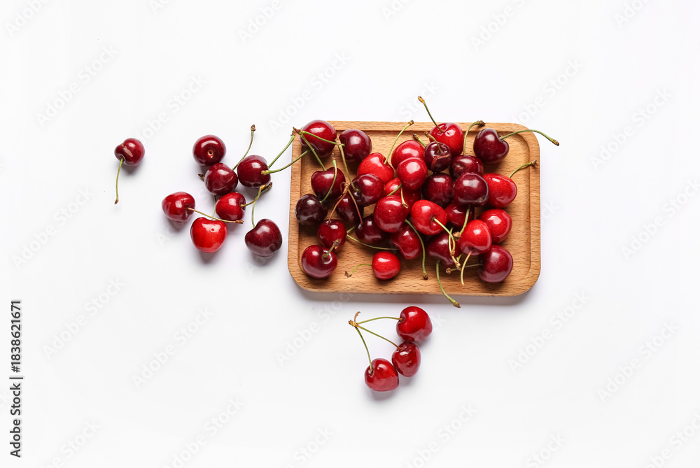 Naklejka premium Wooden board with sweet cherries on white background
