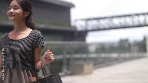 Happy asian woman walking outdoors with shopping bags at mall, joyful shopping fashion, consumer happiness, weekend activity and celebrating purchase, sale promotion, cashback reward after shopping