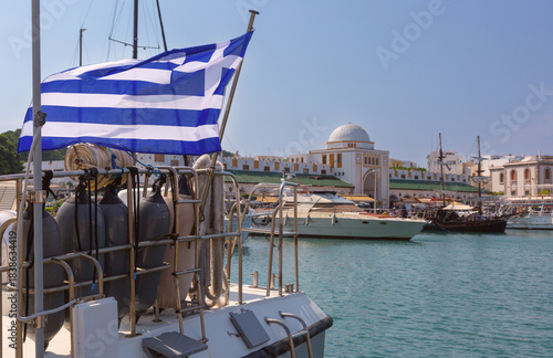 Bilde på lerret Greek flag on boat with Nea Agora and yachts at Mandraki harbor in Rhodes, Greec