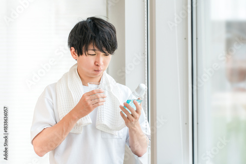 A young Asian man taking care of his bad breath with morning mouthwash
