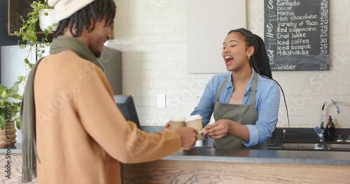 Diverse barista and customer greeting, offering tray, selecting cups, paying for order, copy space