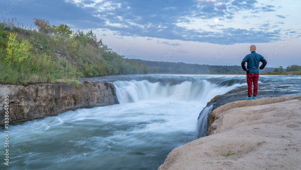 Naklejka premium lonely man contemplating the Norden Chute on Niobrara River in Nebraska, late summer sunrise scenery
