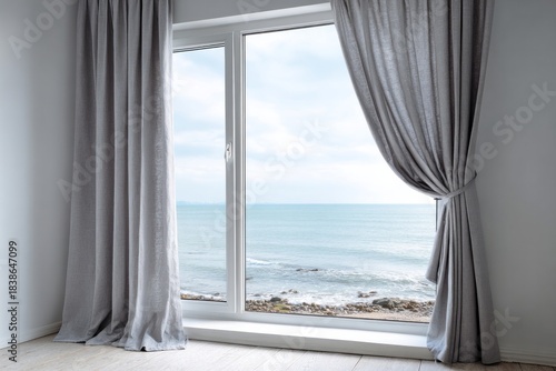 Open curtains reveal a serene ocean view through a window.