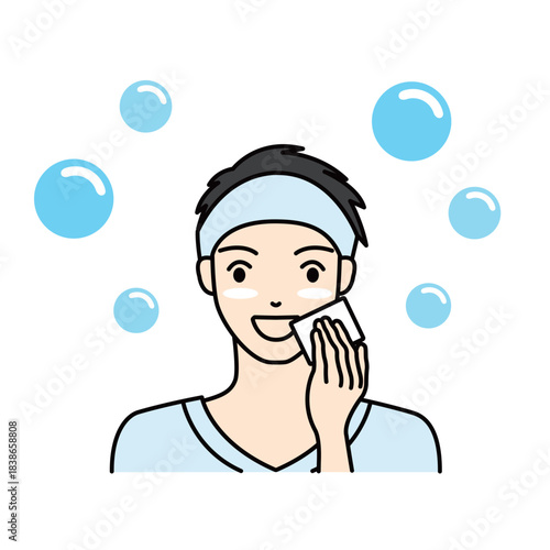 Smiling man wiping his face with a cotton pad during skincare routine