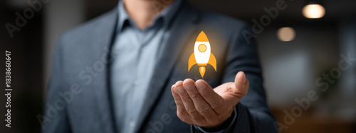 Businessman holding glowing rocket icon in his hand, symbolizing startup growth, innovation and business launch in corporate setting with blurred office background