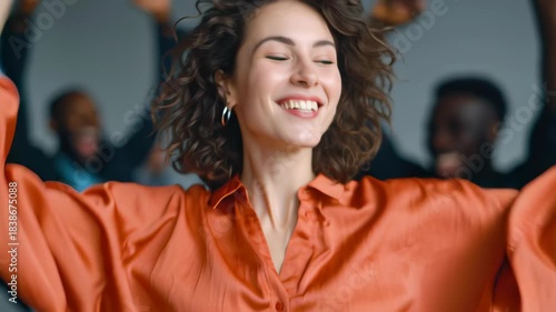 Joyful woman curly hair orange shirt hoop earring smiling face side profile happy crowd office party celebration motion blur confident young woman cheerful smile soft light diverse coworkers modern