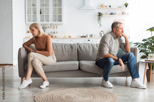 Tableau sur toile Older couple sits apart on a couch in a bright living room, showing tension and emotional distance