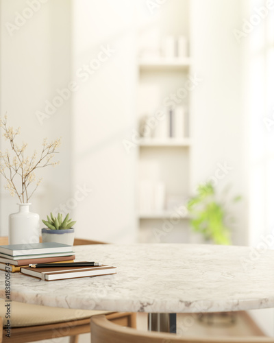 Pencil on book and pot plant on round marble table and wooden chair across bookshelf in living room.