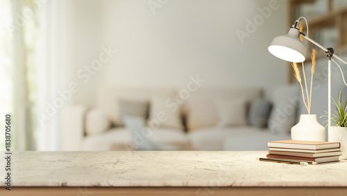 Fototapeta Naklejka Na Ścianę i Meble -  Books and pencil under lamp aside potted plant on marble counter table across sofa in a living room.