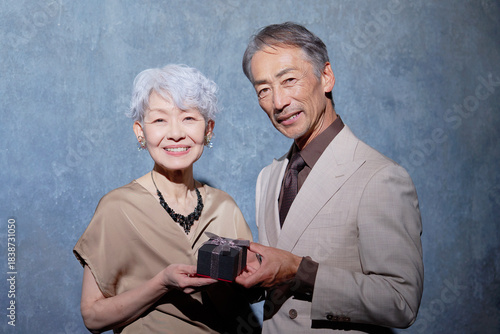 指輪のプレゼントを持つシニア夫婦　ポートレート　カメラ目線