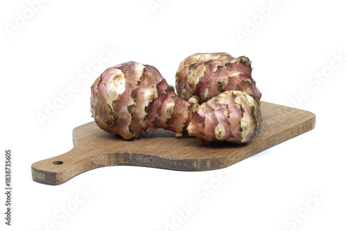 Jerusalem artichokes on a wooden cutting board against a white background