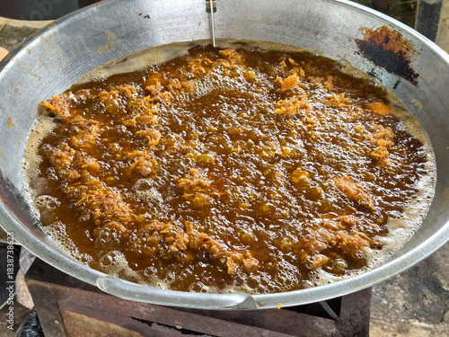 Close-up view of deep crunchy fried chicken batter cooking in boiling oil inside a wide metal wok