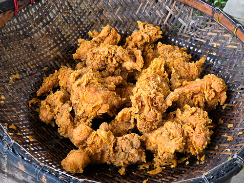 Freshly cooked crunchy fried chicken piled in a woven basket with detailed texture and golden crust