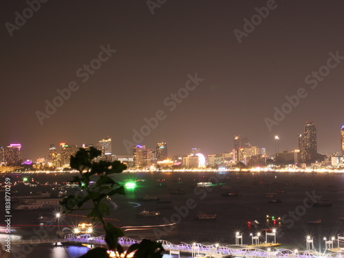 Fireworks lighting up the night sky in Pattaya, creating a vibrant and colorful display over the city and ocean. The bright explosions illuminate the coastline, capturing the festive atmosphere of thi