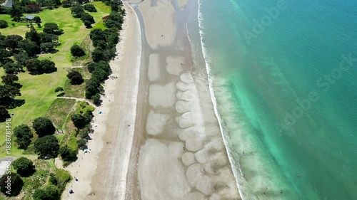 Direct overhead drone aerial of Long Bay beach showing sand textures and clear water in Auckland New Zealand.