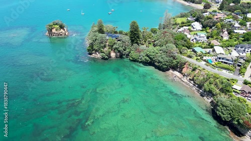 Drone aerial scene near Winstones Cove showing clear water and green coastal landscape in Auckland New Zealand.
