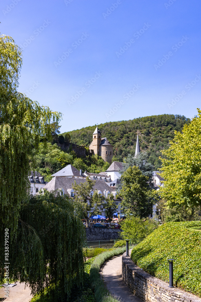 Fototapeta premium Esch-sur-Sure, Wiltz, Grand-Duche de Luxembourg, September 07, 2025, Quiet walk past greenery, Slightly inclined route towards charming town square surrounded by nature and local life