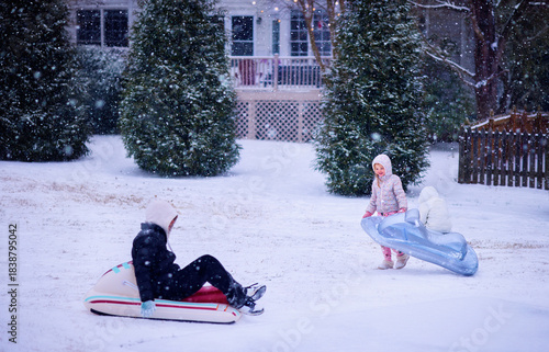 Children Sledding and Playing in a Snowy Backyard - Inflatable Sleds and Fun Winter Activity in Motion