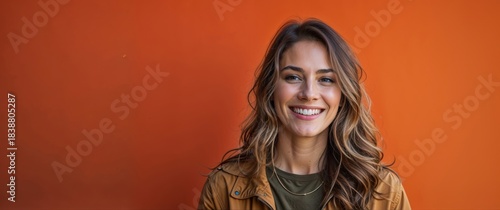 Young woman smiling in front of vibrant orange background