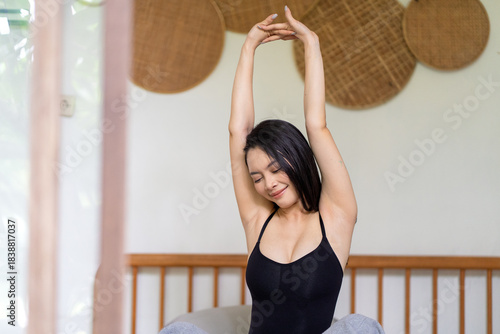 Asian Woman Stretching Happily After Waking Up in a Cozy Bedroom