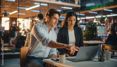 Professional colleagues collaborating on project with laptop in modern open office