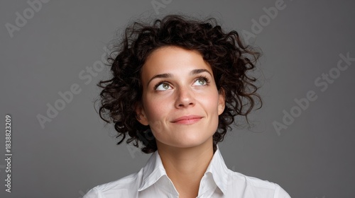 Woman with curly hair and glasses, smiling at camera.