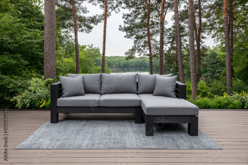 Modern outdoor sectional sofa set on deck by serene lake surrounded by tall trees in early morning light