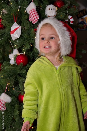 Cute little girl with Santa hat standing in front of Christmas tree