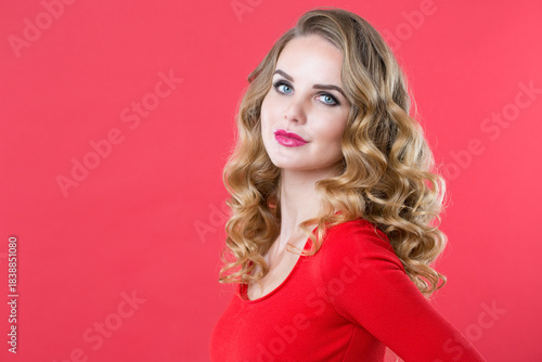 Wallpaper Mural Woman with long curly blonde hair and blue eyes wearing a red top, posing with her head turned to the side against a pink Torontodigital.ca
