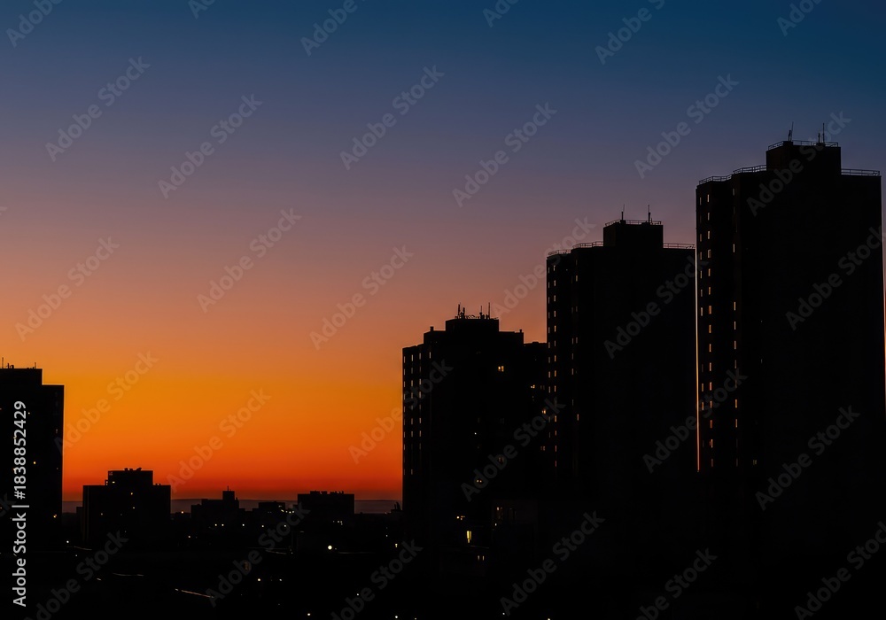 Naklejka premium Dramatic urban profile visible at twilight. Tall structures form a deep black silhouette against the vibrant, colorful background of the fading evening sky ,ambient ,financial ,tower
