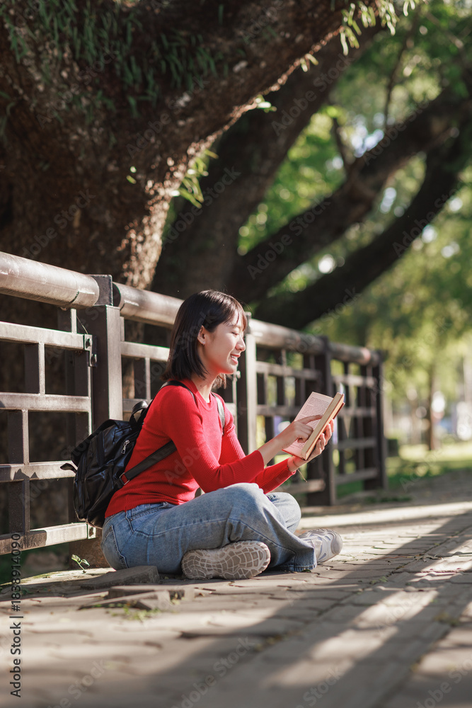 Obraz premium Young woman enjoying reading book in park