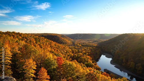 Scenic overview of a river valley with colorful trees during autumn under a vibrant blue sky with sunlight