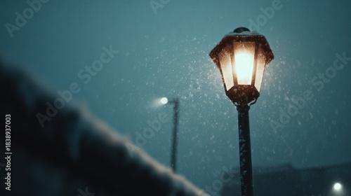 Glowing street lamp in a snowy winter night with falling snow creating a calm cinematic blue atmosphere