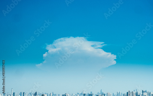  : Lone Fluffy Cloud Over Distant City Skyline on Sunny Day