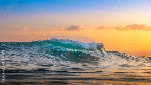 Fototapeta Naklejka Na Ścianę i Meble -  A beautiful view capturing an ocean wave cresting under a vibrant orange and blue sunset sky providing a peaceful seascape scene.
