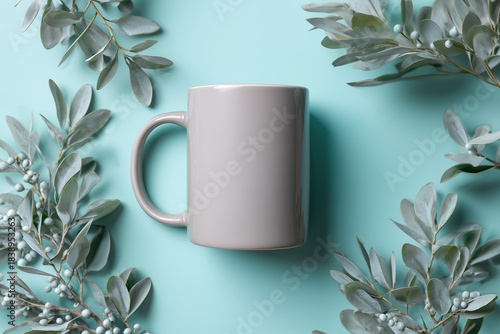 Gray ceramic mug centered on a mint turquoise background, framed by eucalyptus branches and berries in a minimalist flat lay composition.