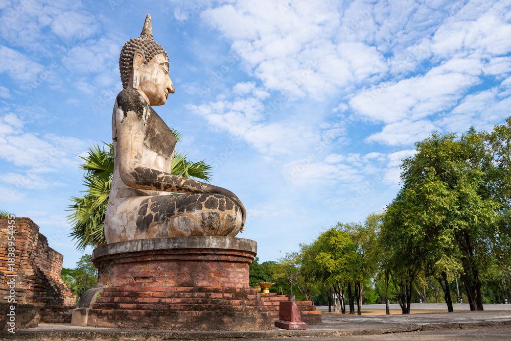 Obraz premium Ancient sculpture of a seated Buddha on the ruins of the Wat Mae Chon buddhist temple. Sukhothai, Old town.Thailand