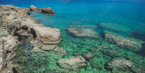 beautiful transparent water and blue of a sea in a Sardinia beach with granite rock and hill background