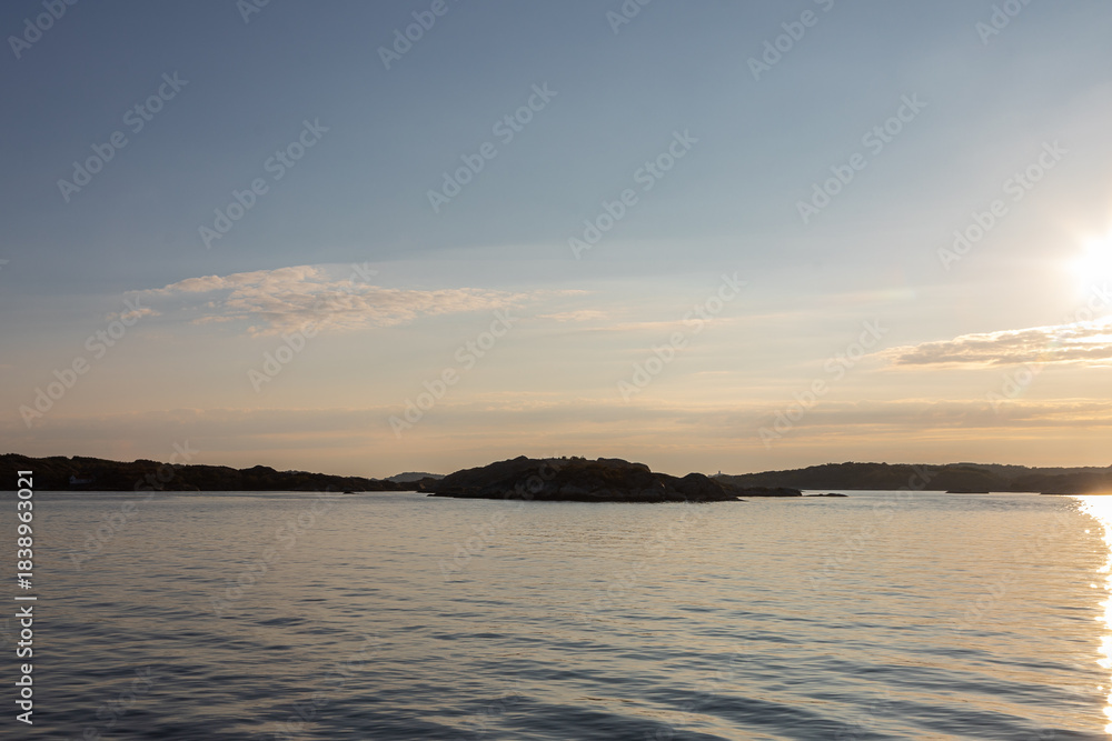 Obraz premium Beautiful summer evening with a spectacular sunset over the Gothenburg Archipelago and the calm water of the North Sea seen from the rocky coastline of the small island Vrango with a swimming jetty