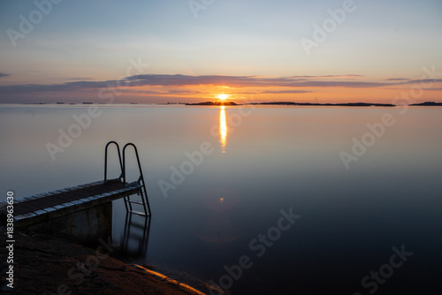 Beautiful summer evening with a spectacular sunset over the Gothenburg Archipelago and the calm water of the North Sea seen from the rocky coastline of the small island Vrango with a swimming jetty