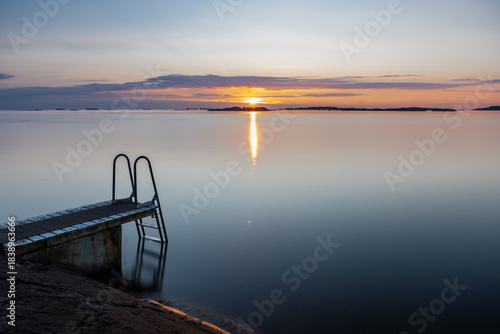 Beautiful summer evening with a spectacular sunset over the Gothenburg Archipelago and the calm water of the North Sea seen from the rocky coastline of the small island Vrango with a swimming jetty