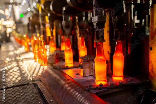 Glass factory, production of glass containers. Molten glass is blown into molds. Robotics in industry. Modern technologies, robotic machines produce products. Technological work at the plant.